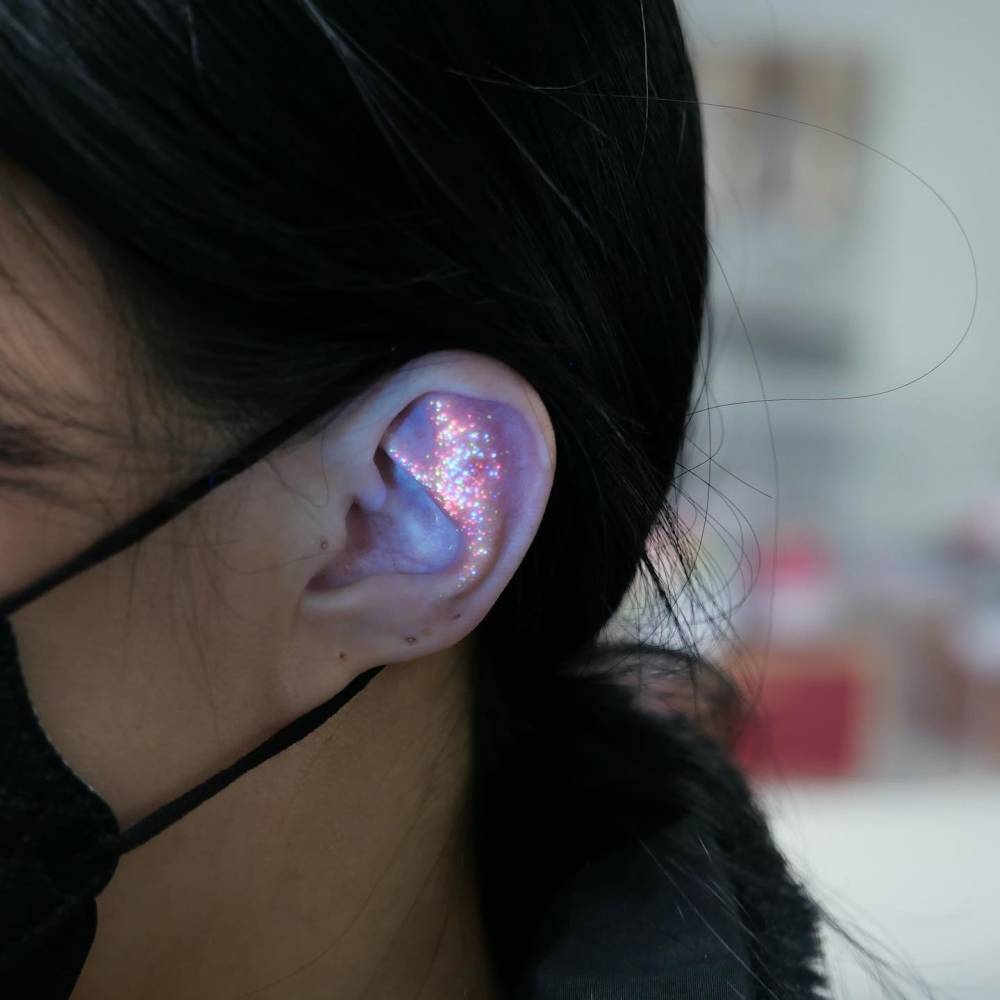Glitter effect tattoo located on the ear.