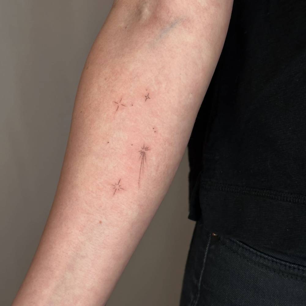 Sparkling stars tattoo in minimalistic style done on the inner forearm.