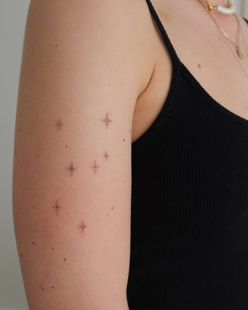 Sparkling stars tattoo located on the upper arm.
