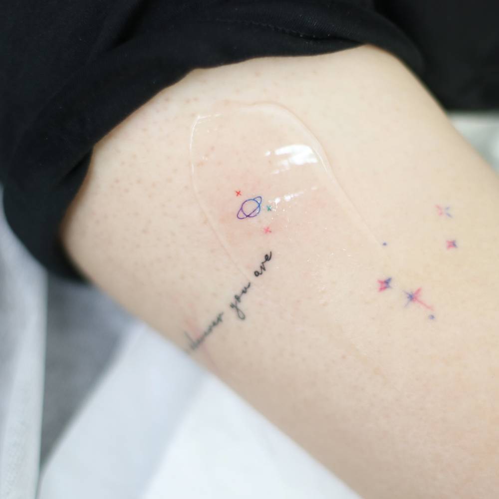 Little spectrum Saturn and stars tattoo located on the upper arm.