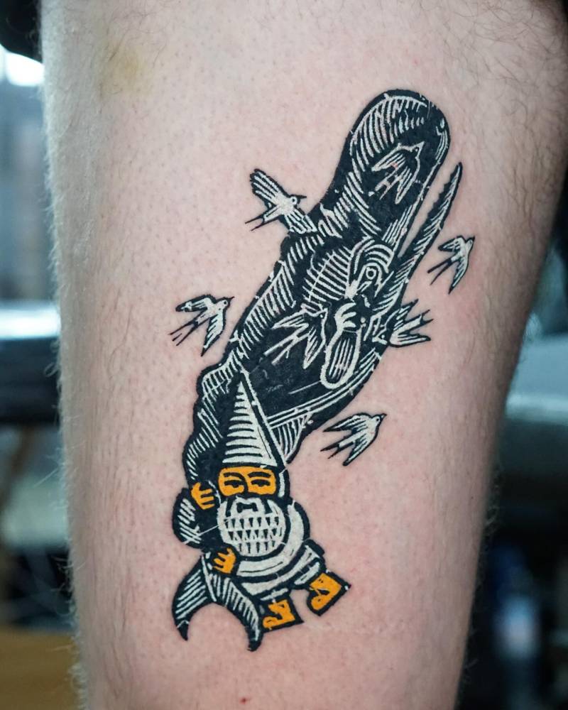 Gnome, whale and swallows tattooed on the thigh.