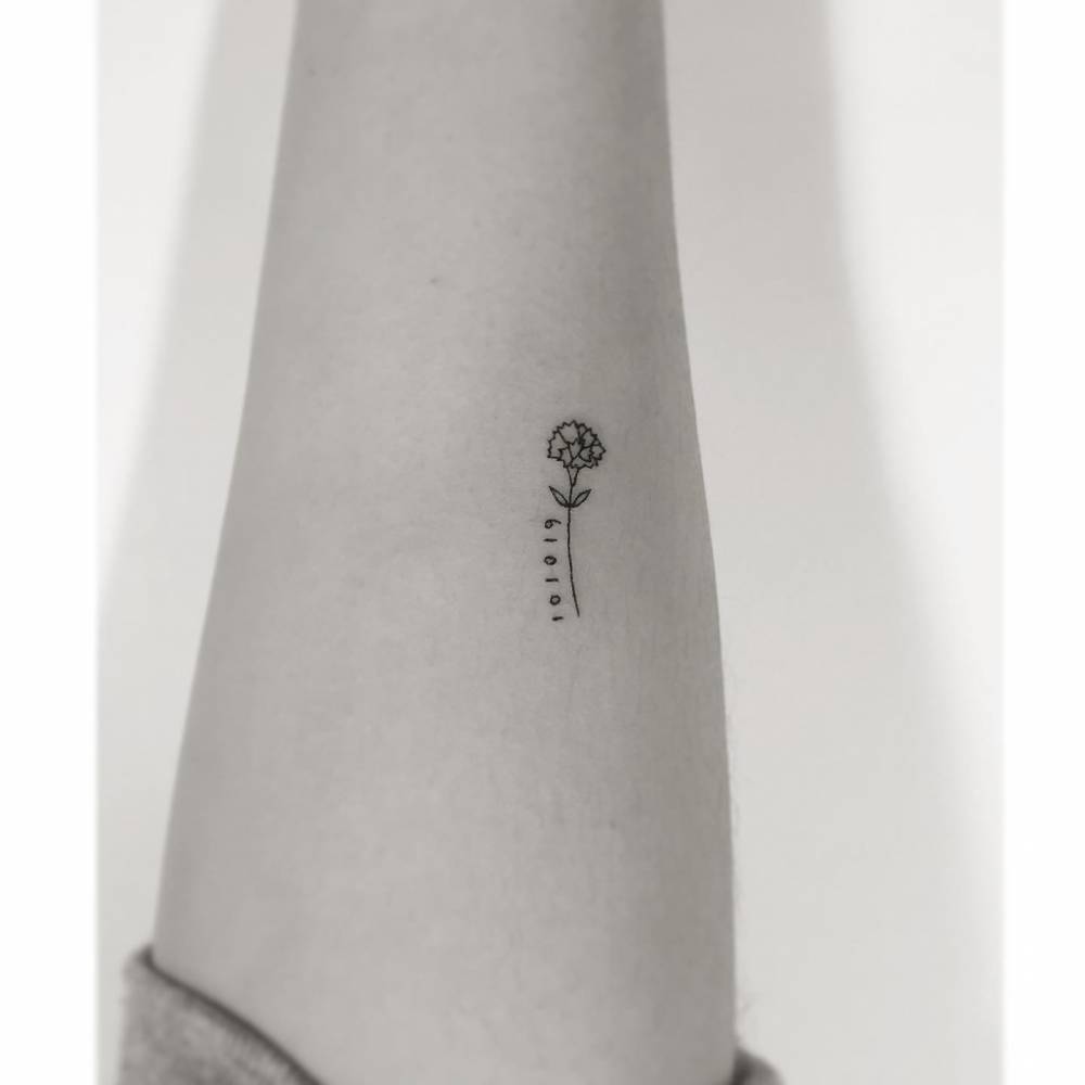 Flower and date tattoo in minimalistic style located on the inner forearm.