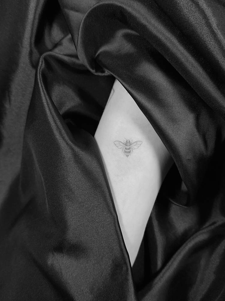 Bee tattoo placed on the rib, done in fine line style.
