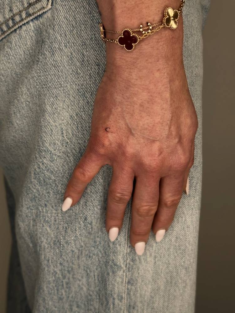 Tiny minimalistic letter "C" tattooed on the hand.