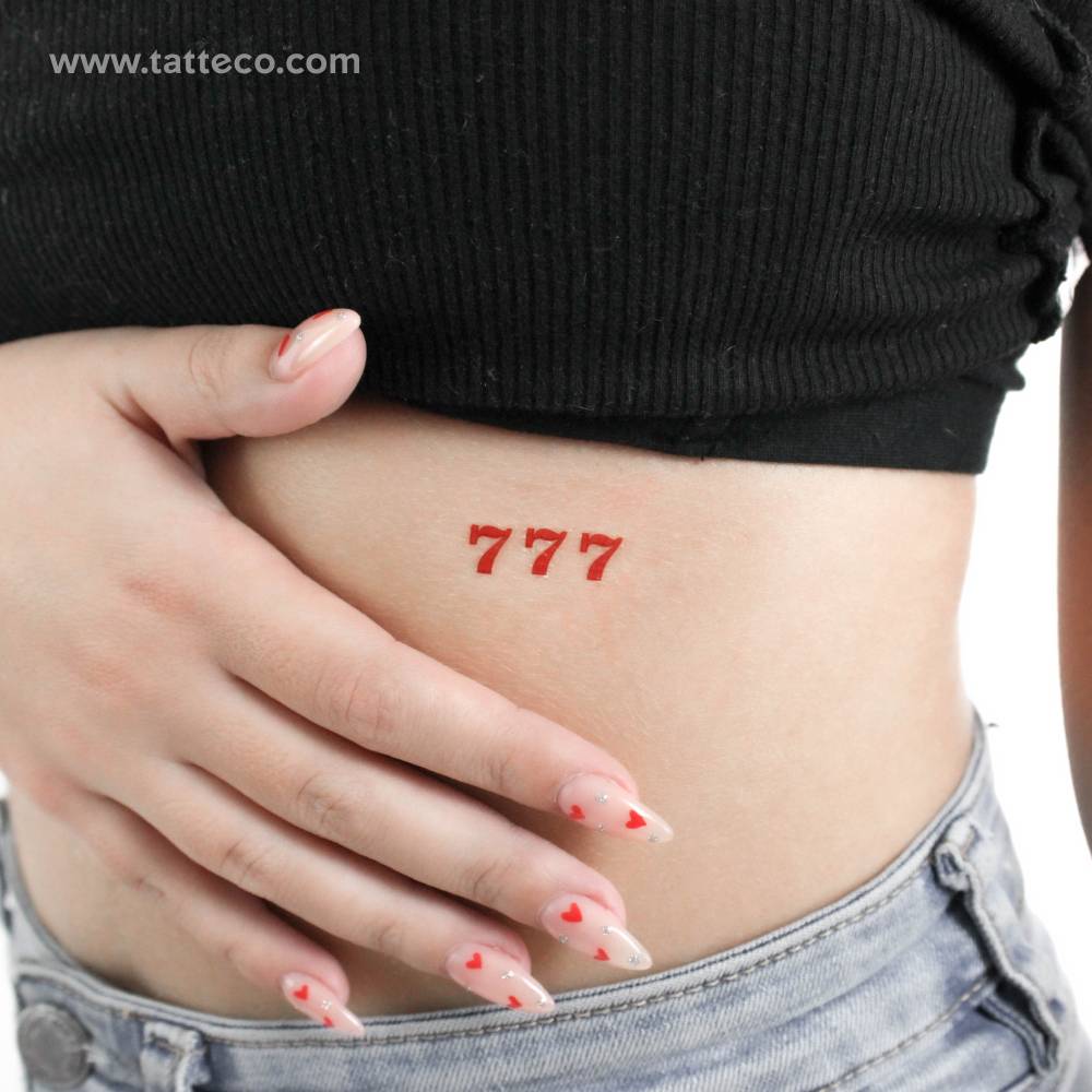 Red angel number "777" temporary tattoo placed on the rib.