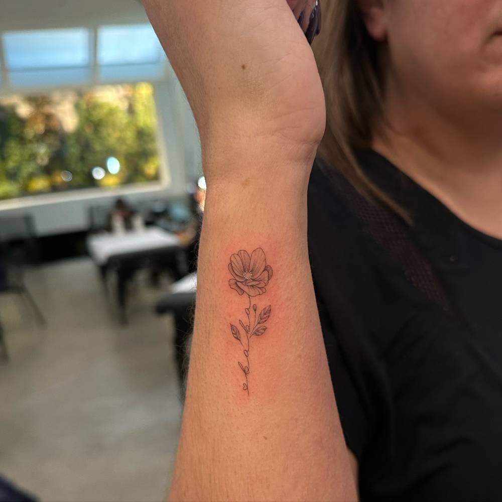 Flower and word "baba" tattooed on the wrist.