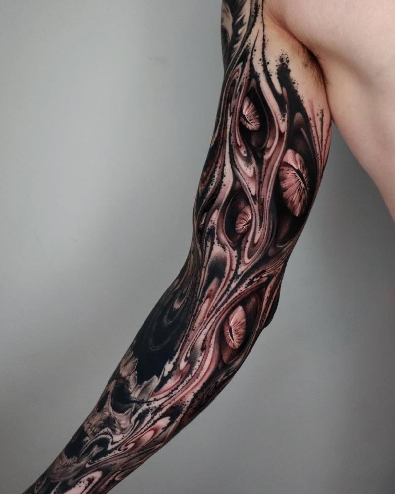 Abstract eyes tattoo located on the inner arm.