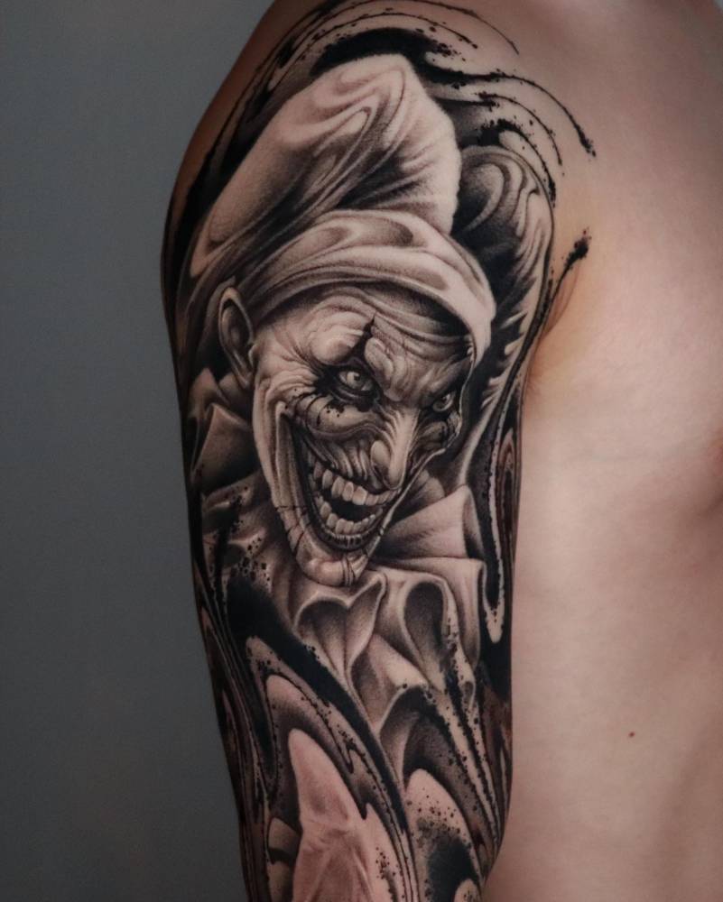 Black and grey style The Joker portrait tattoo located on the upper arm (healed).