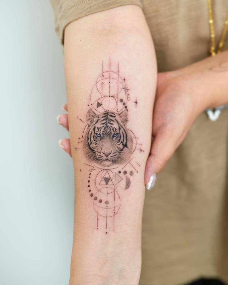 Graphic style tiger portrait tattoo located on the inner forearm.