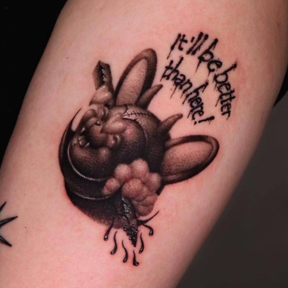 Devil teddy bear tattoo located on the upper arm.