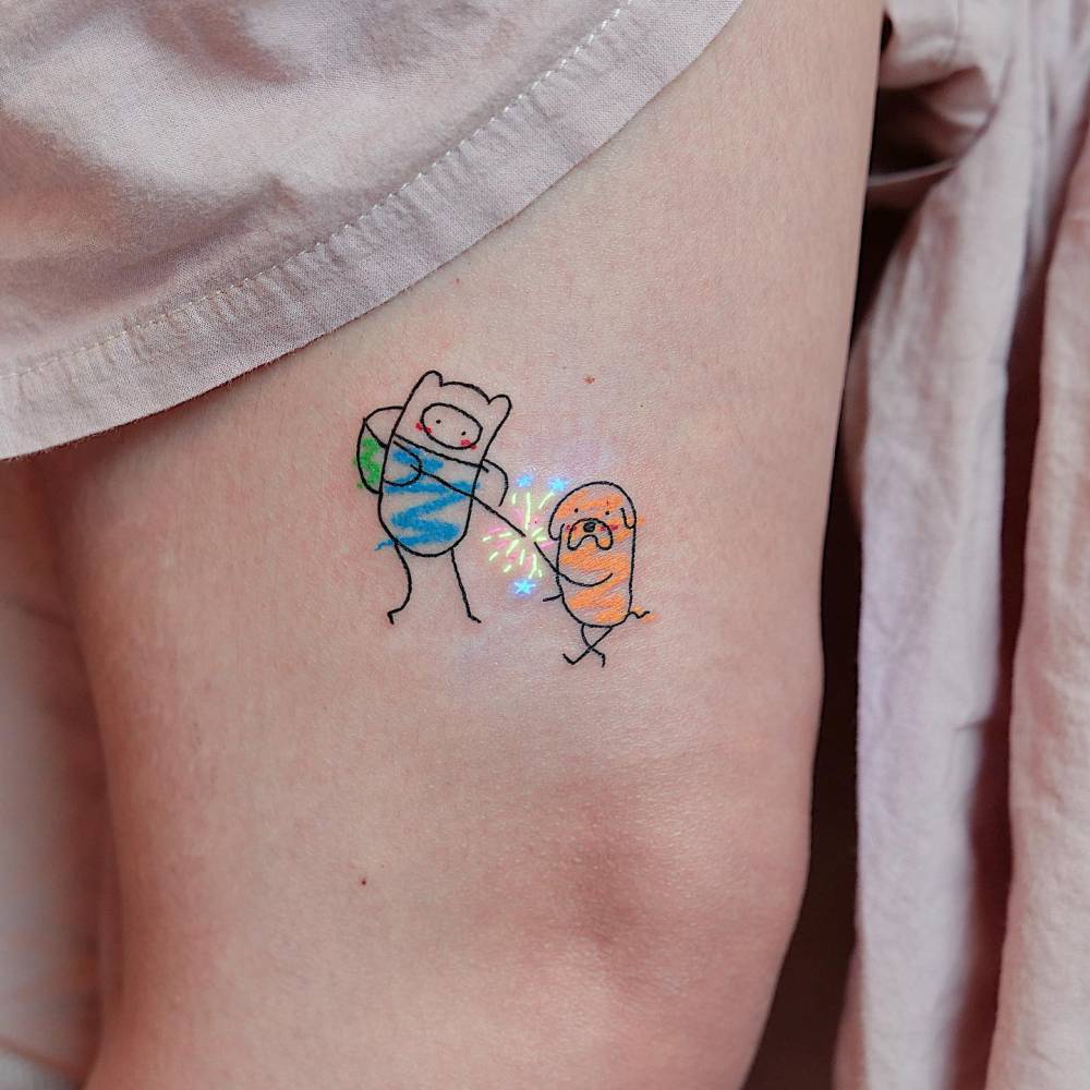 Finn and Jake tattooed on the thigh, cartoon style.