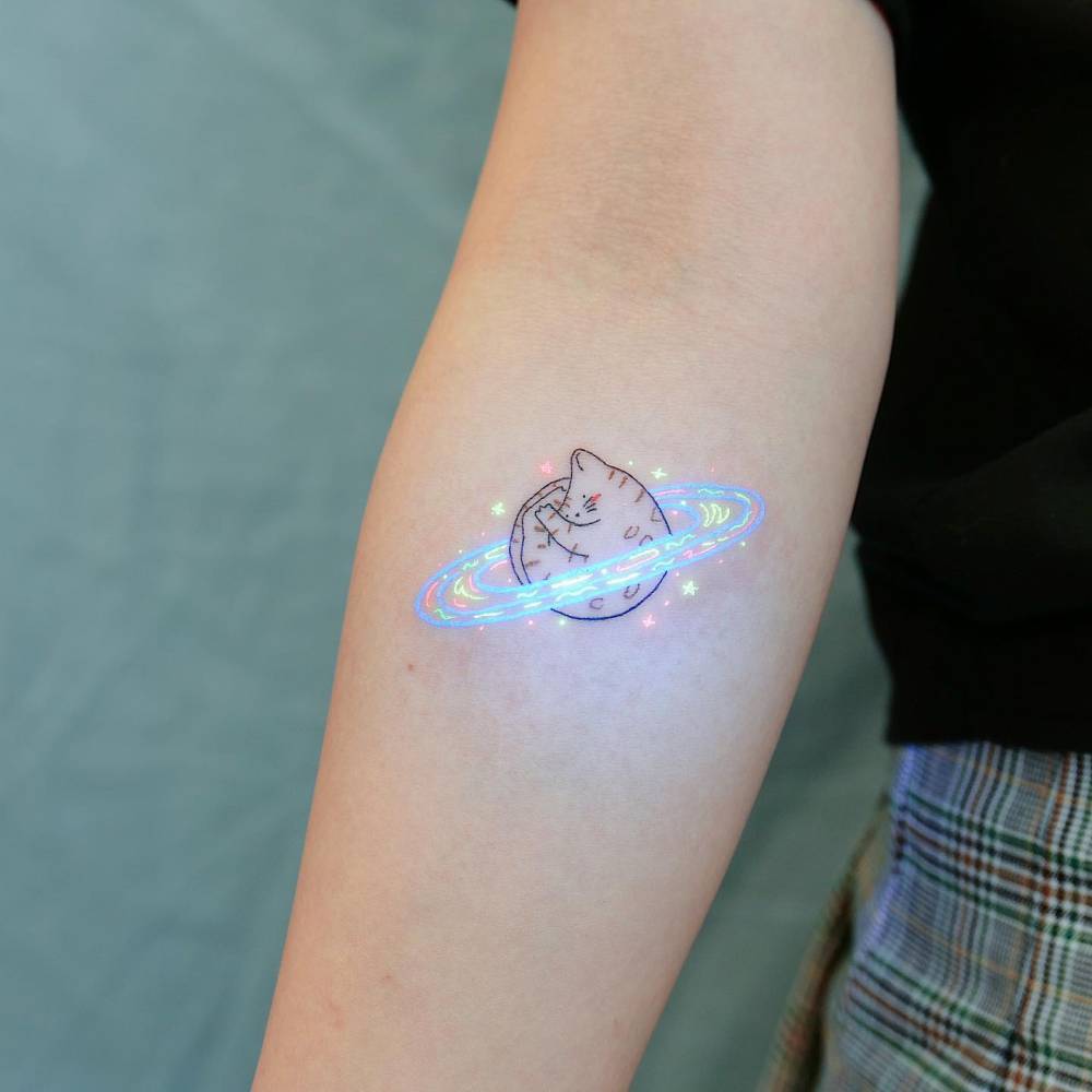 Cartoon style Saturn cat tattoo located on the inner forearm.