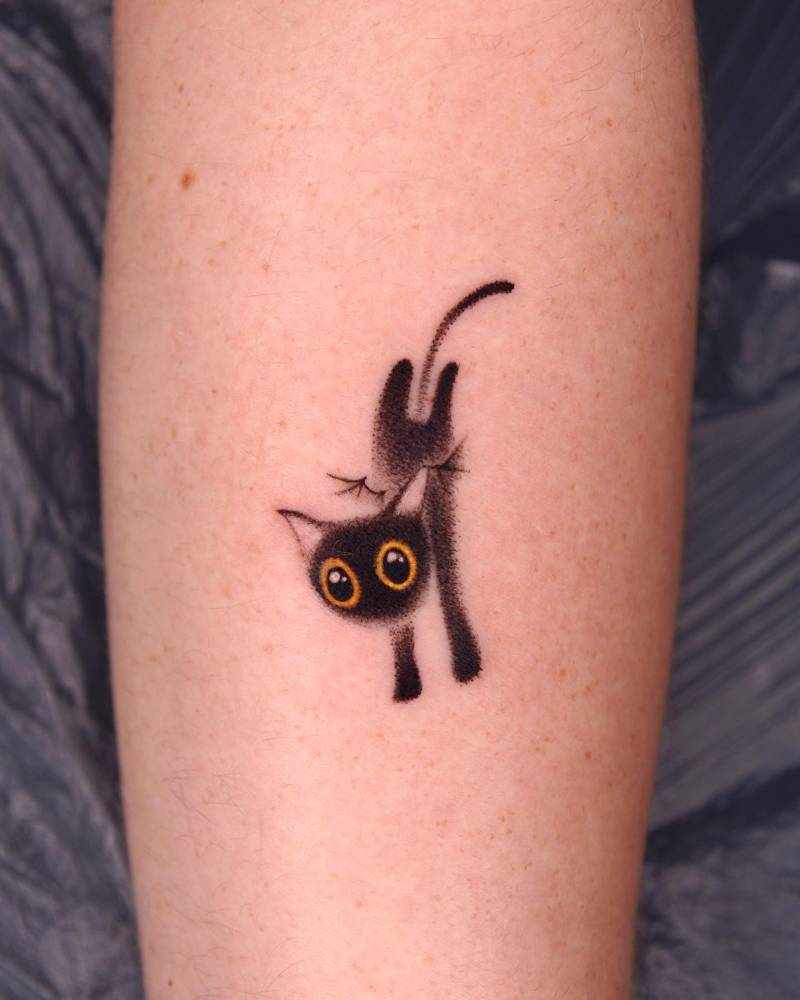 Cute black cat tattoo located on the forearm, cartoon style.