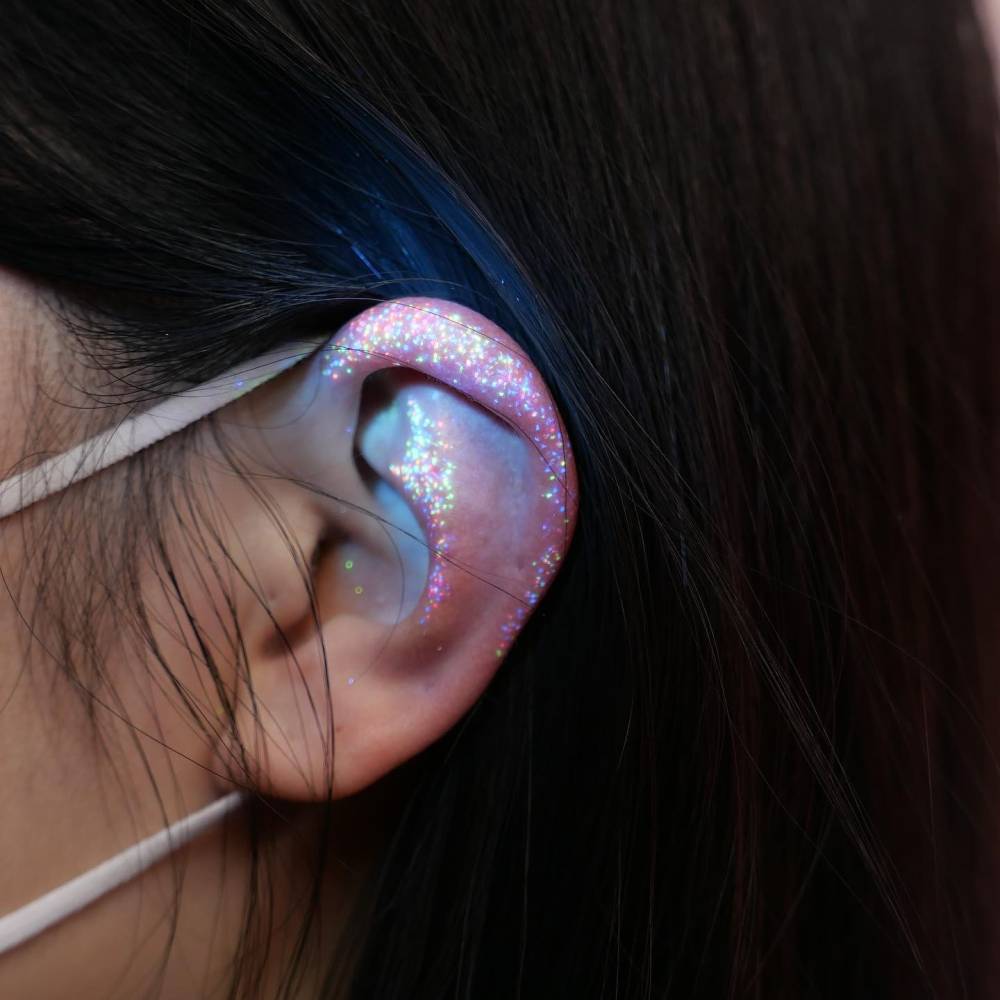 Glitter effect UV ink tattoo located on the ear.