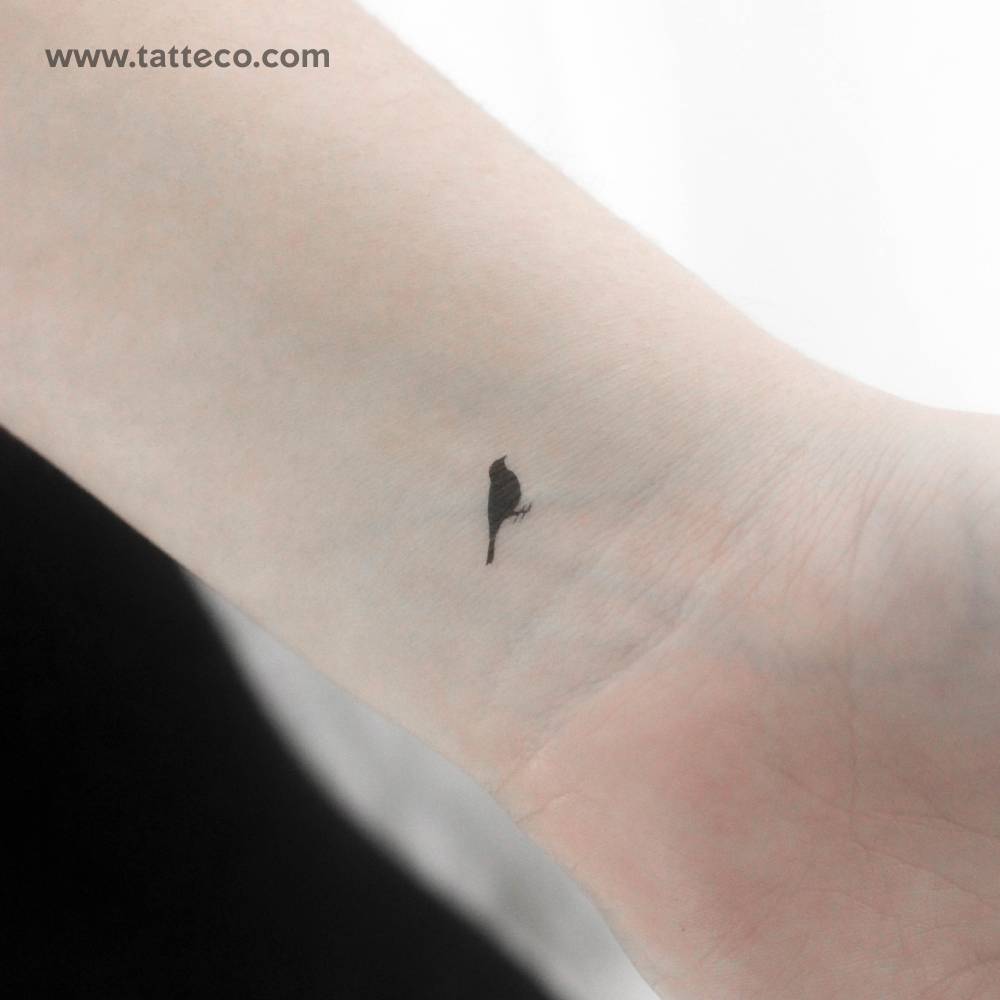 Tiny minimalistic standing bird temporary tattoo located on the wrist.