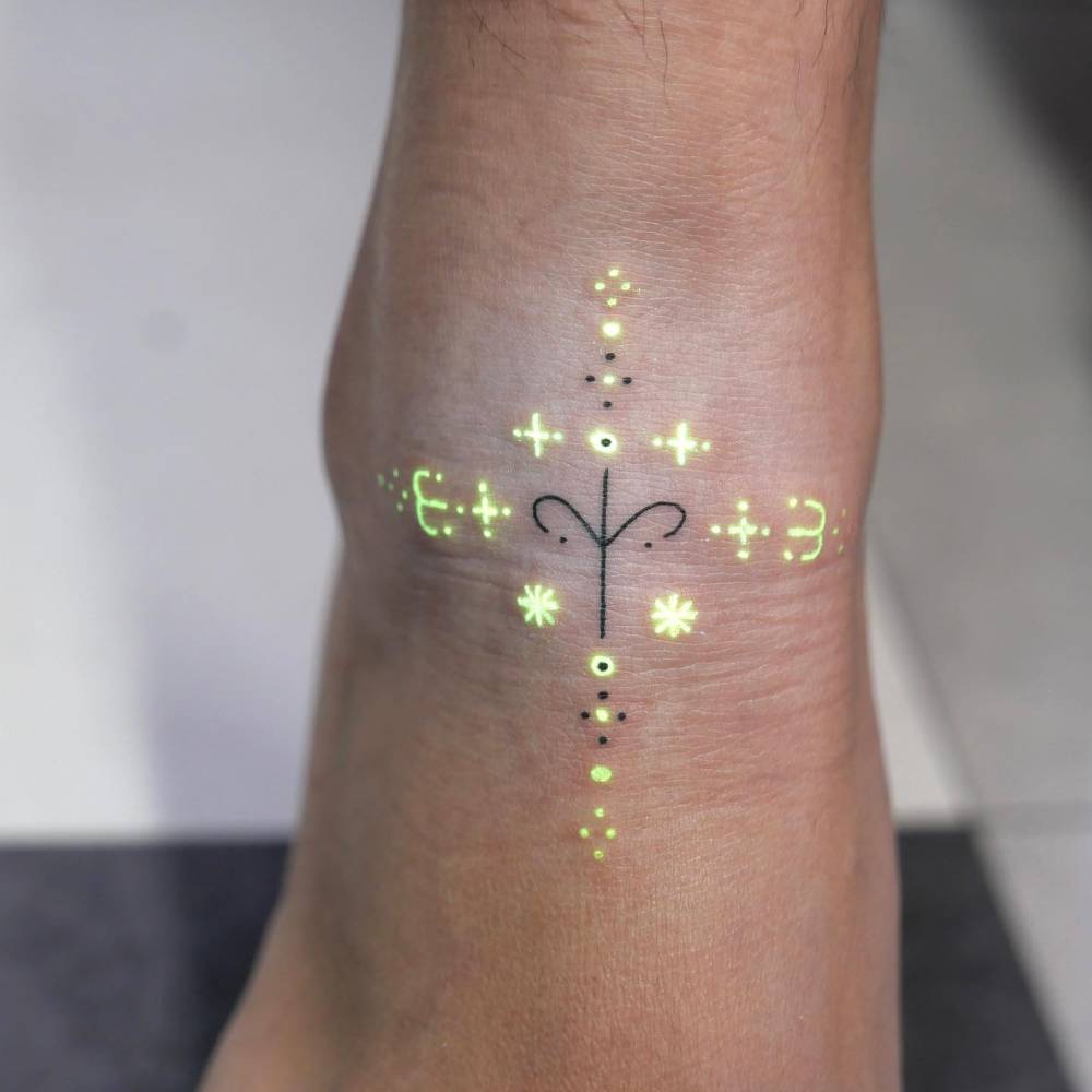 Ornamental design in UV ink tattooed on the ankle.