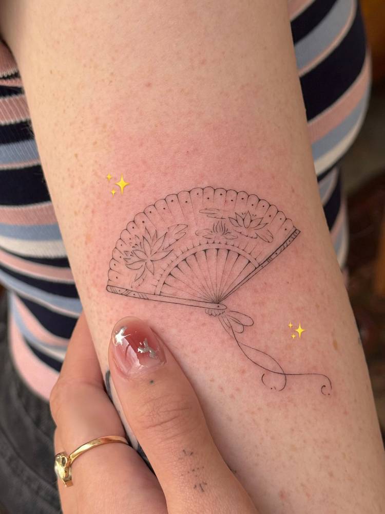 Fine line style hand fan tattoo located on the upper arm.