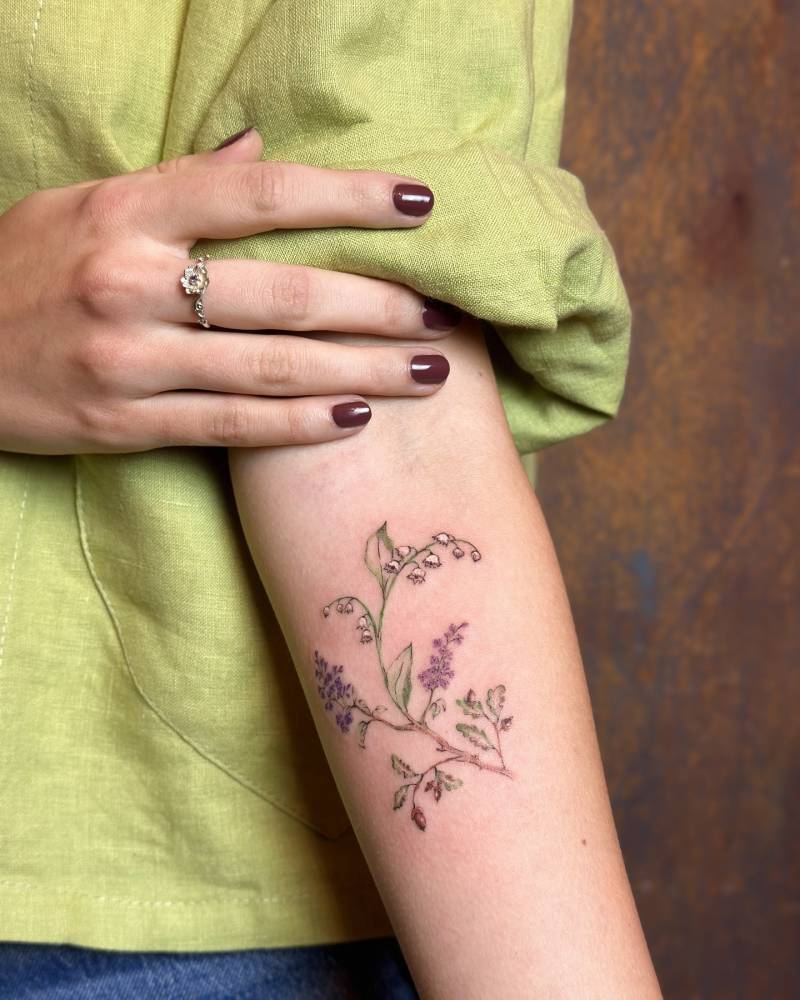 Lily of the valley flowers tattooed on the inner forearm.