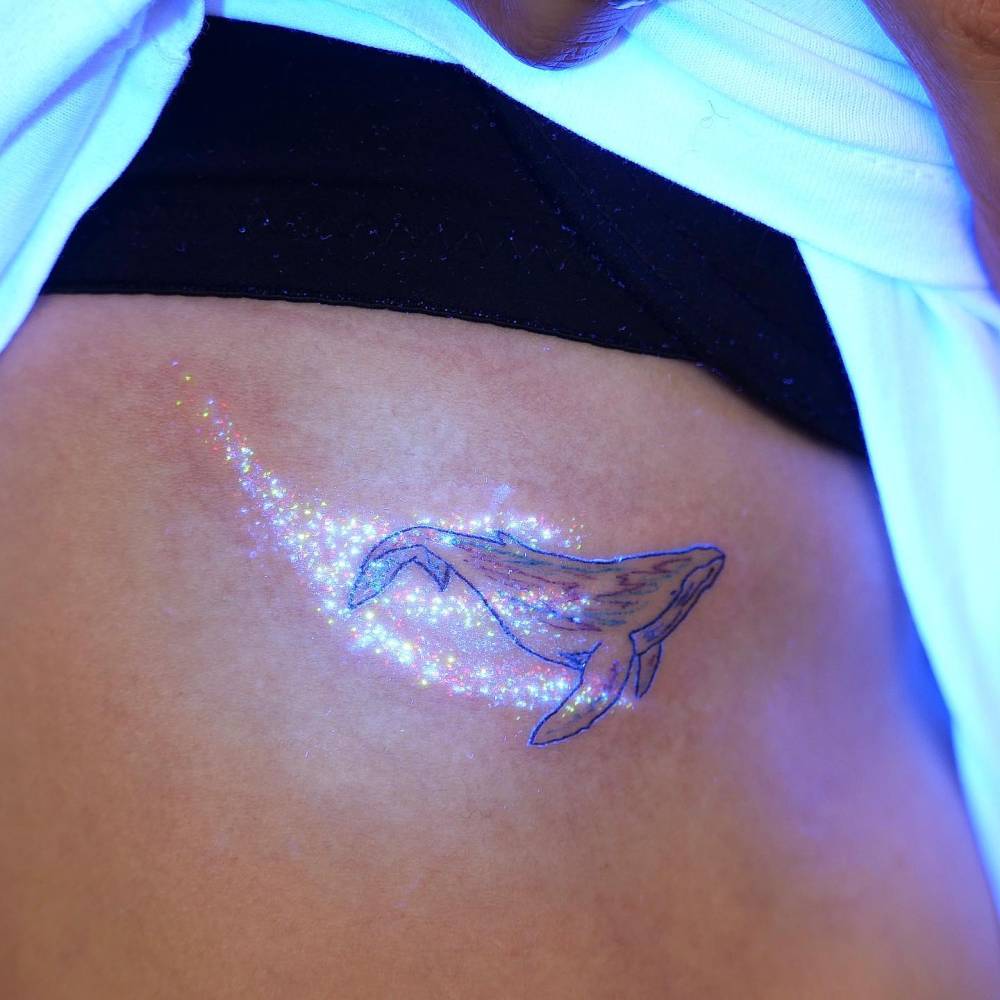 Whale tattoo in illustrative style located on the rib.