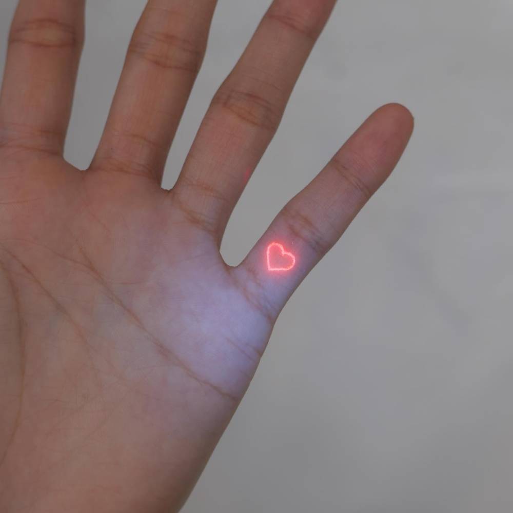 Red heart tattoo done with UV ink located on the finger.