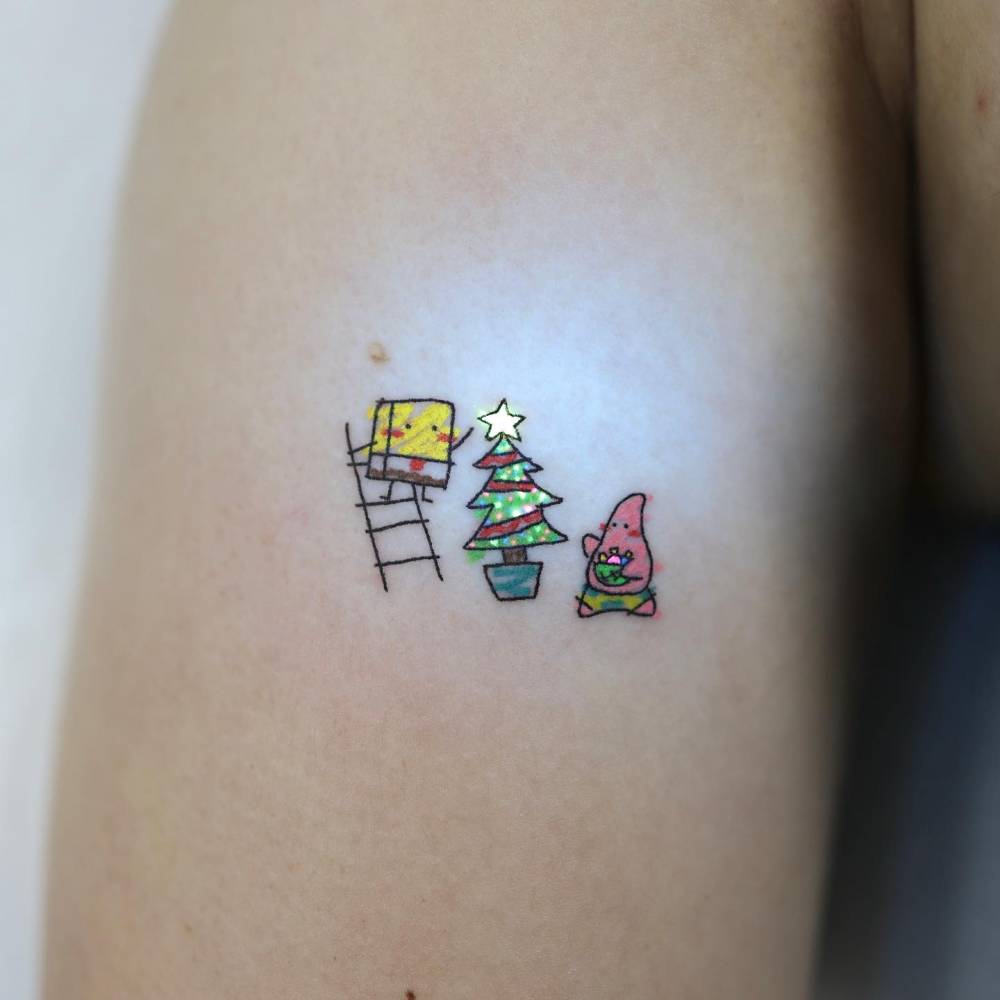 Spongebob and Patrick Star building a Christmas tree tattooed on the upper arm.
