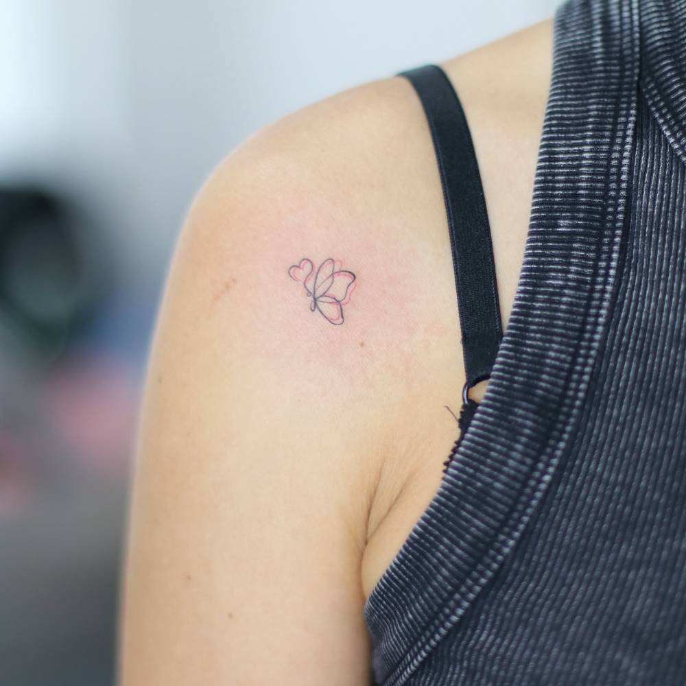 Fine line style butterfly tattoo placed on the shoulder.
