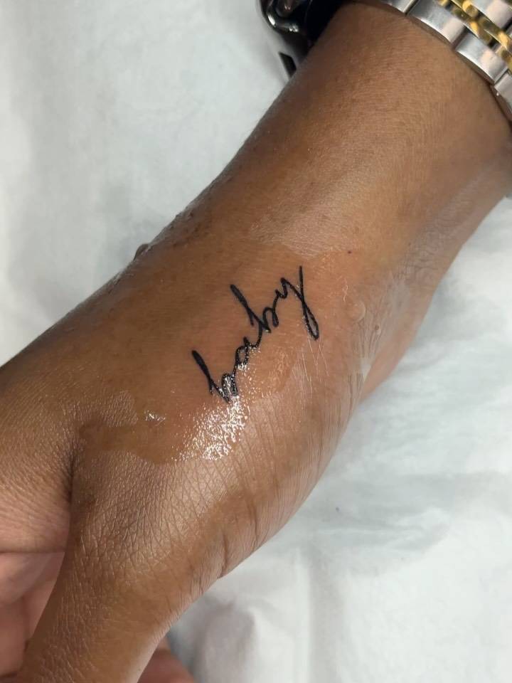 Lettering tattoo of the word baby located on the hand.