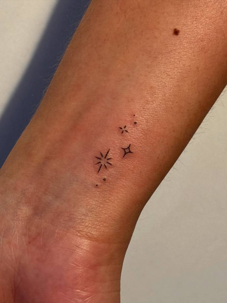 Sparkling stars tattoo in minimalistic style located on the wrist.