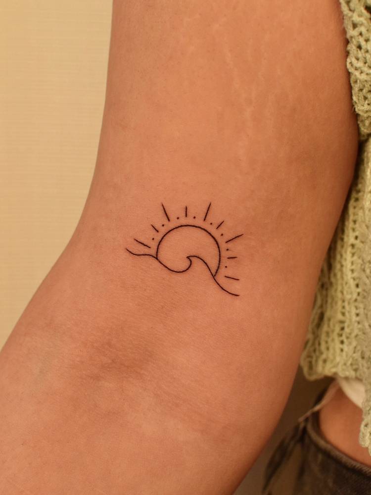 Sun and wave tattoo located on the bicep, minimalistic style.