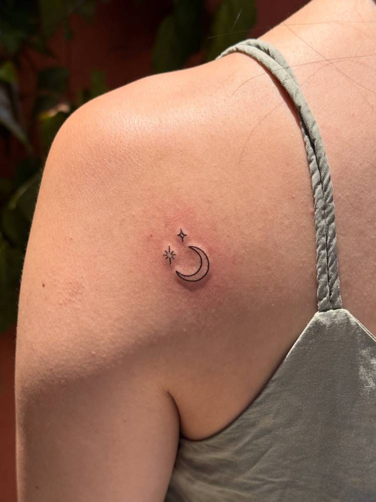 Crescent moon and stars tattooed on the shoulder blade, minimalistic style.