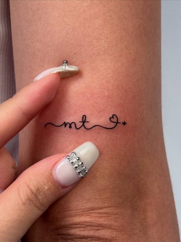 Initials, airplane and heart tattoo located on the tricep.