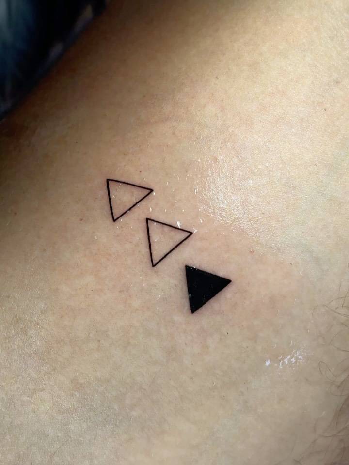 Minimalistic little triangles tattooed on the inner arm.