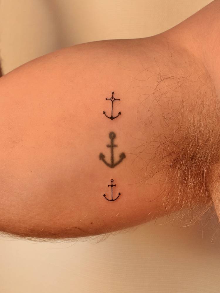 Anchors in minimalistic style tattooed on the inner arm.