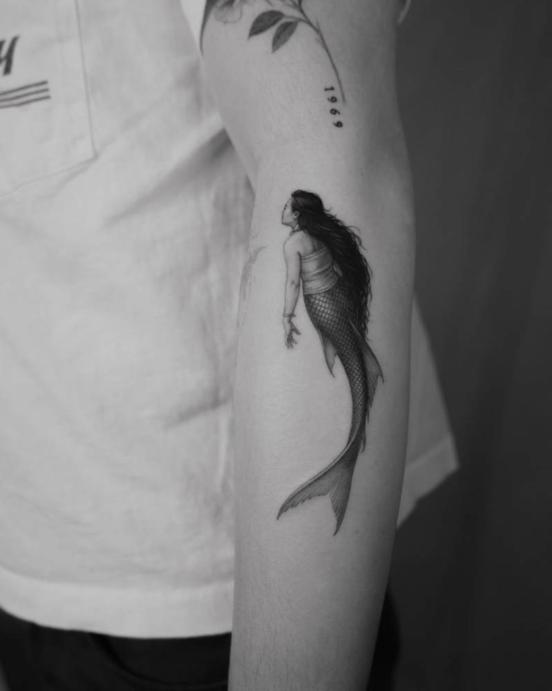 Mermaid tattoo located on the forearm, micro-realistic style.