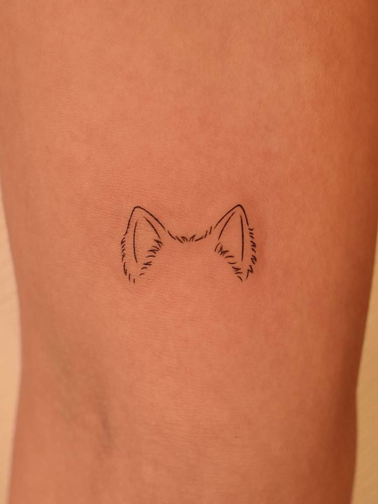 Dog ears in fine line style tattooed on the inner arm.