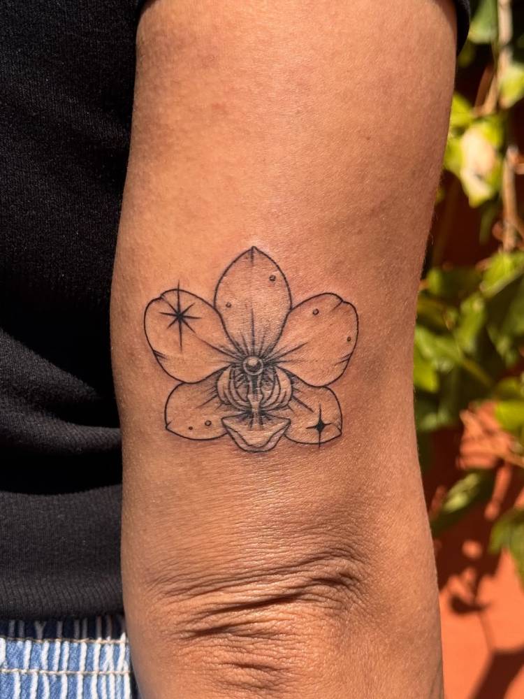 Orchid tattoo in illustrative style placed on the tricep.