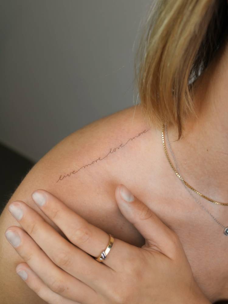 "Live more, love more" lettering tattoo placed on the top of shoulder.
