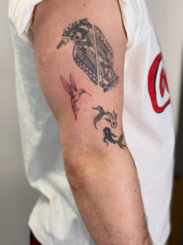 Little hummingbird tattoo placed on the upper arm, micro-realistic style.
