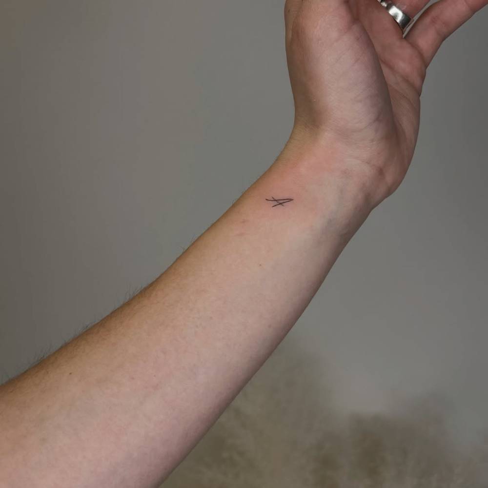Letter "A" tattoo located on the wrist, minimalistic style.