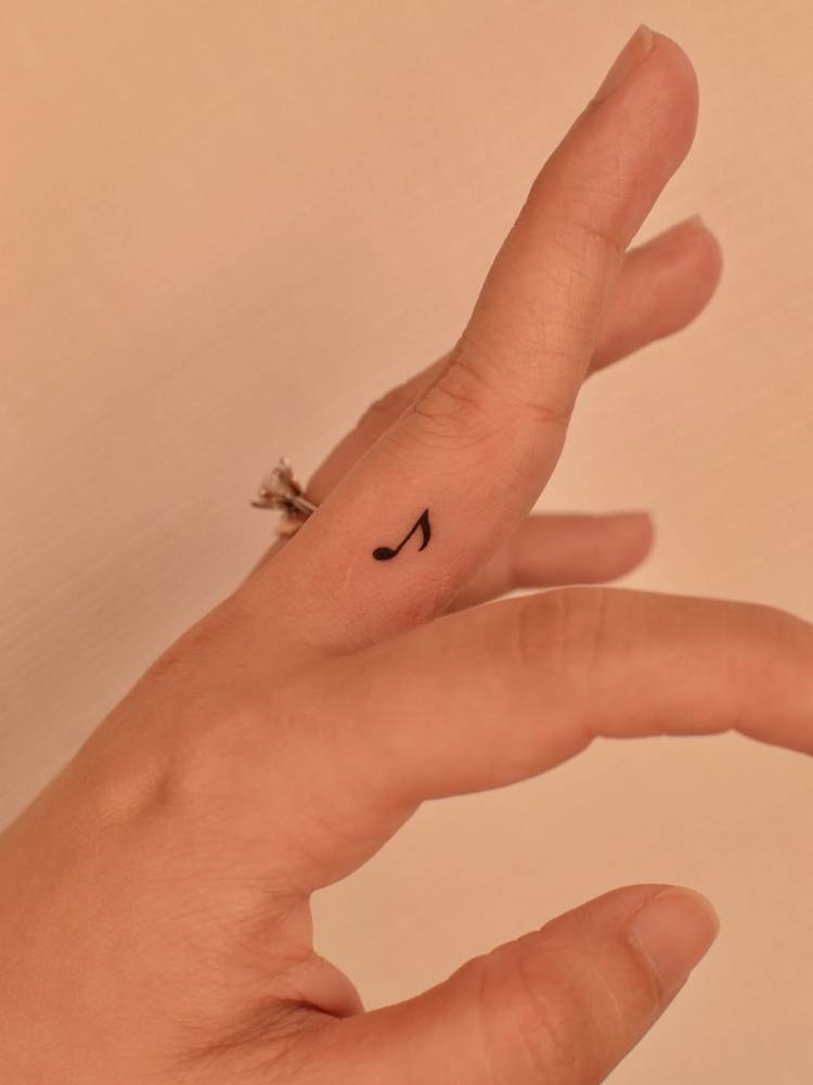 Quaver tattoo located on the finger, done in minimalistic style.