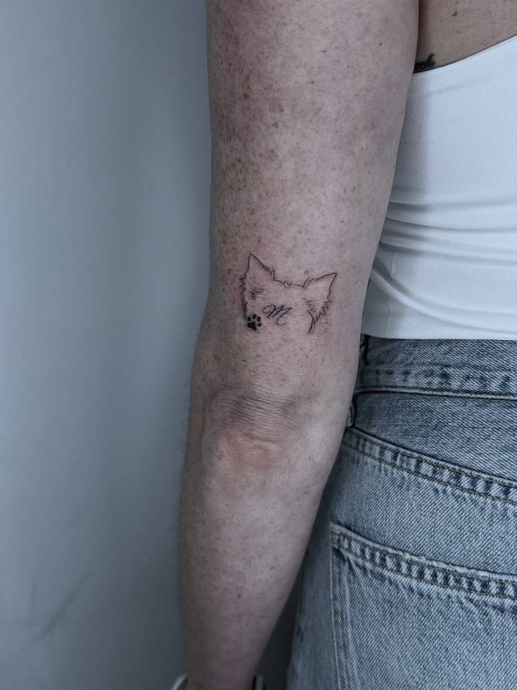 Dog ears and initial tattoo located on the tricep.