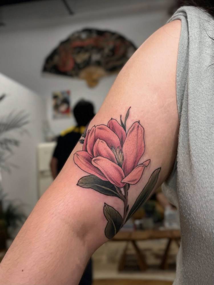 Illustrative style magnolia flower tattoo placed on the upper arm.