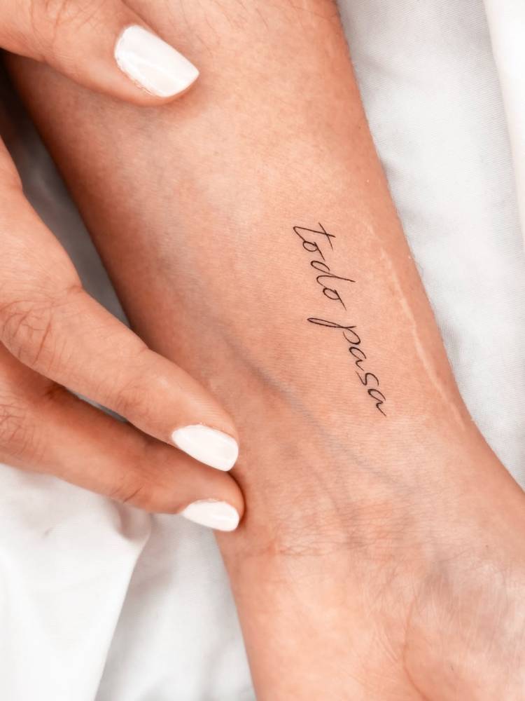 Handwritten font "todo pasa" lettering tattoo placed on the wrist.