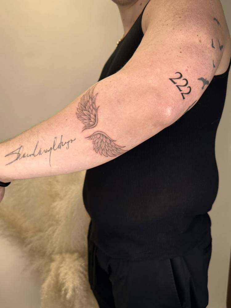 Angel wings tattoo placed on the forearm, done in illustrative style.