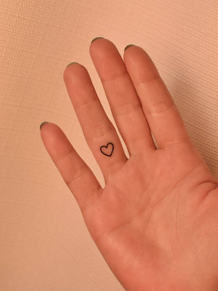 Tiny minimalistic heart tattooed on the finger.