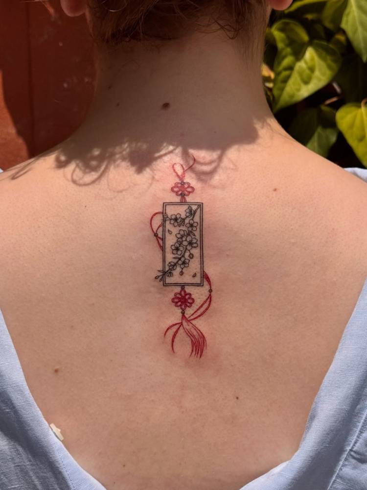 Norigae tattoo located on the upper back, done in fine line style.