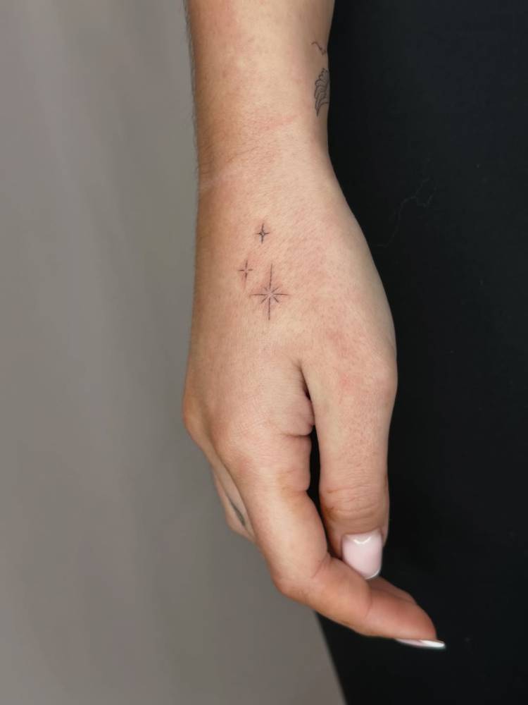 Sparkling stars tattoo in minimalistic style placed on the hand.