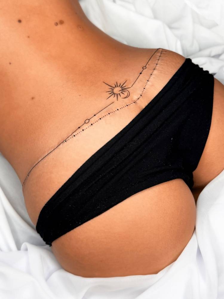 Ornamental sun and moon tattoo located on the lower back.