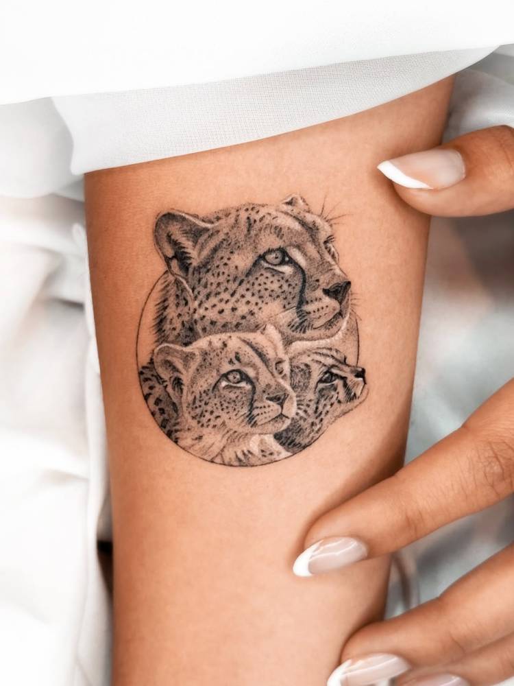 Cheetah family portrait tattooed on the inner forearm, micro-realistic style.