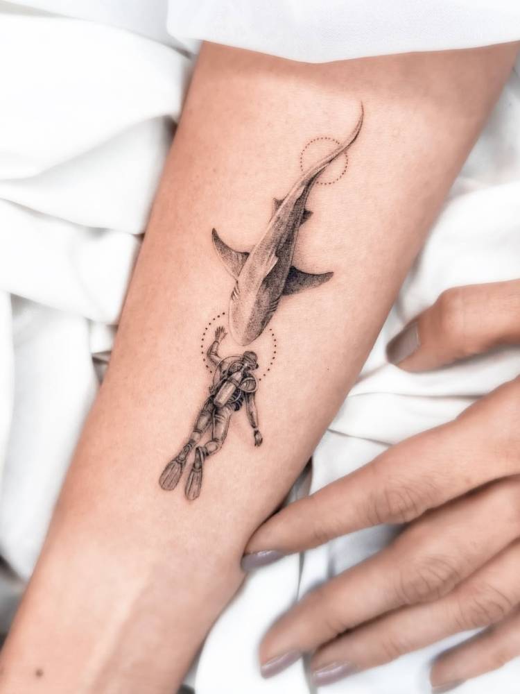 Diver and shark tattoo in micro-realistic style located on the inner forearm.